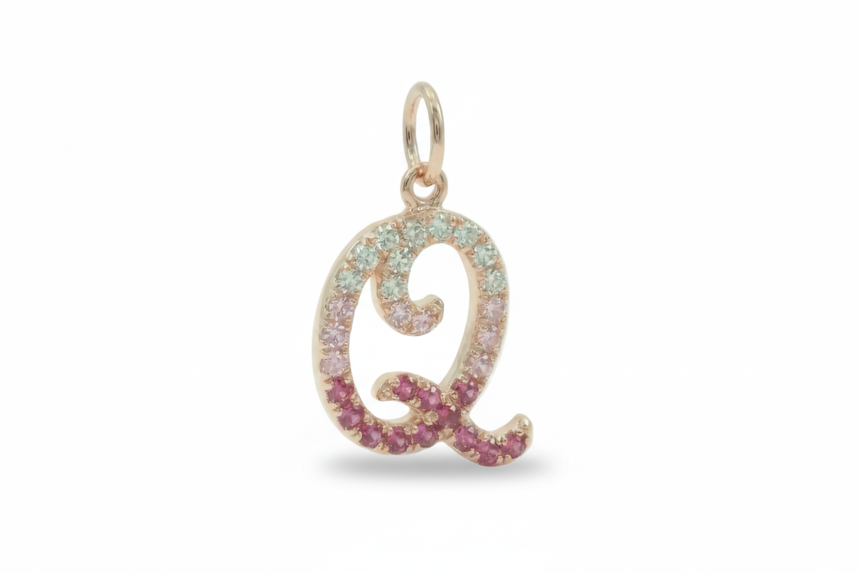 Gold pendant with letter 'Q' and pink gemstones on a white background