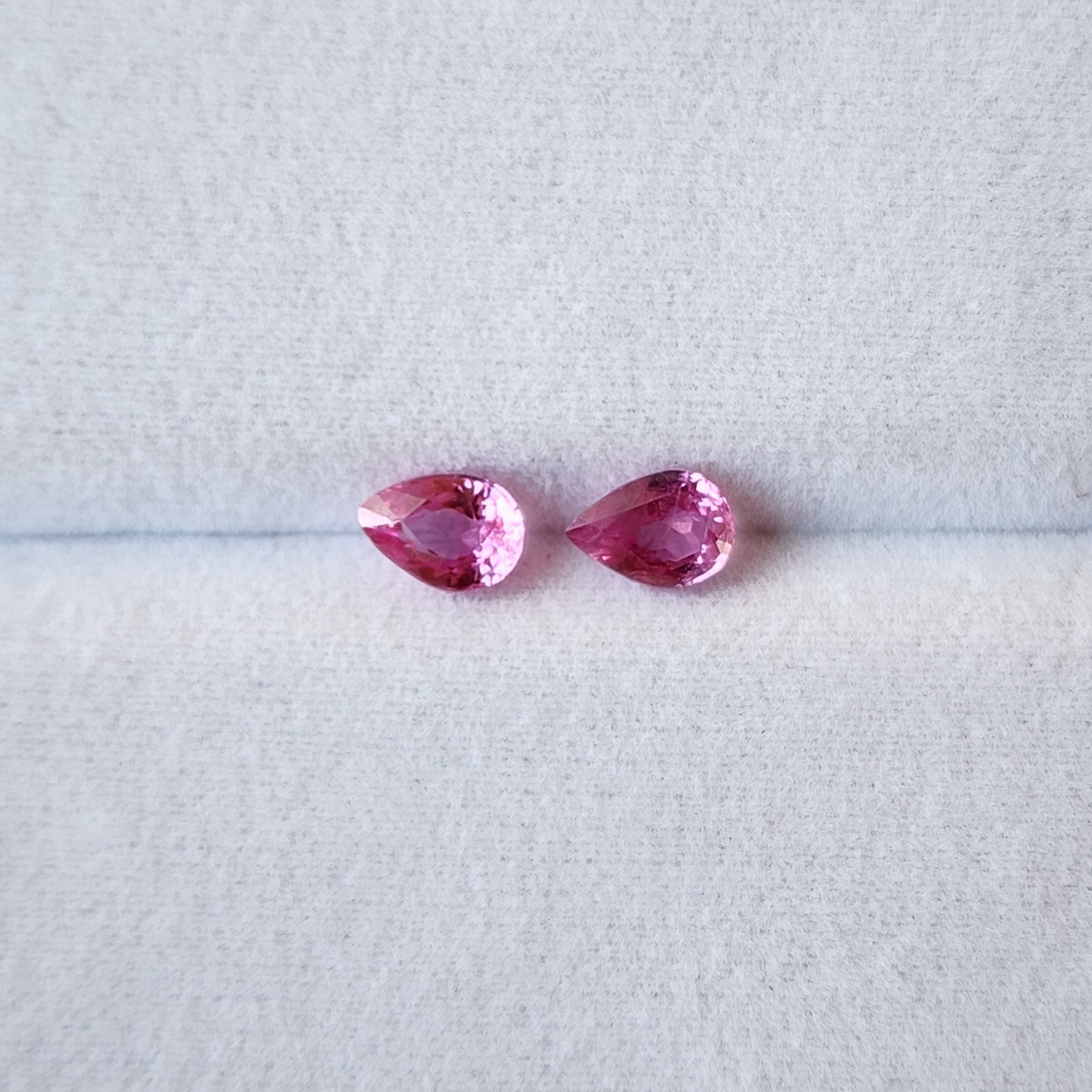 Two pink gemstones on a light gray background
