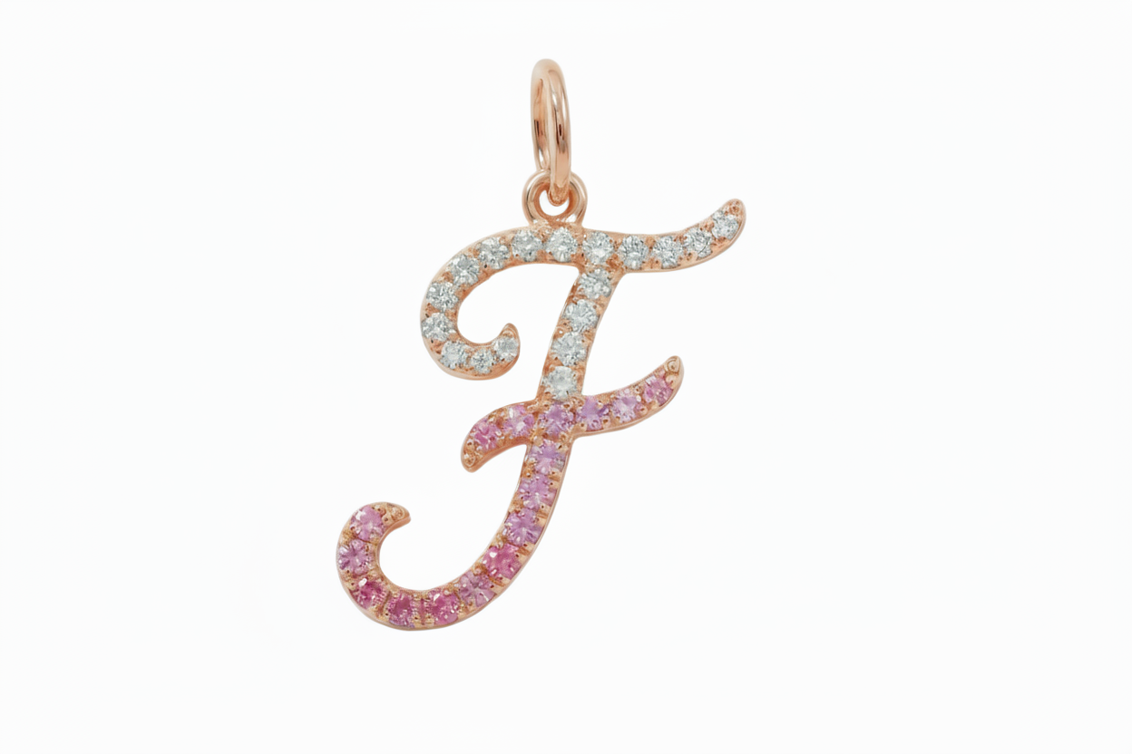 Rose gold letter 'F' pendant with pink and clear gemstones on a light gray background
