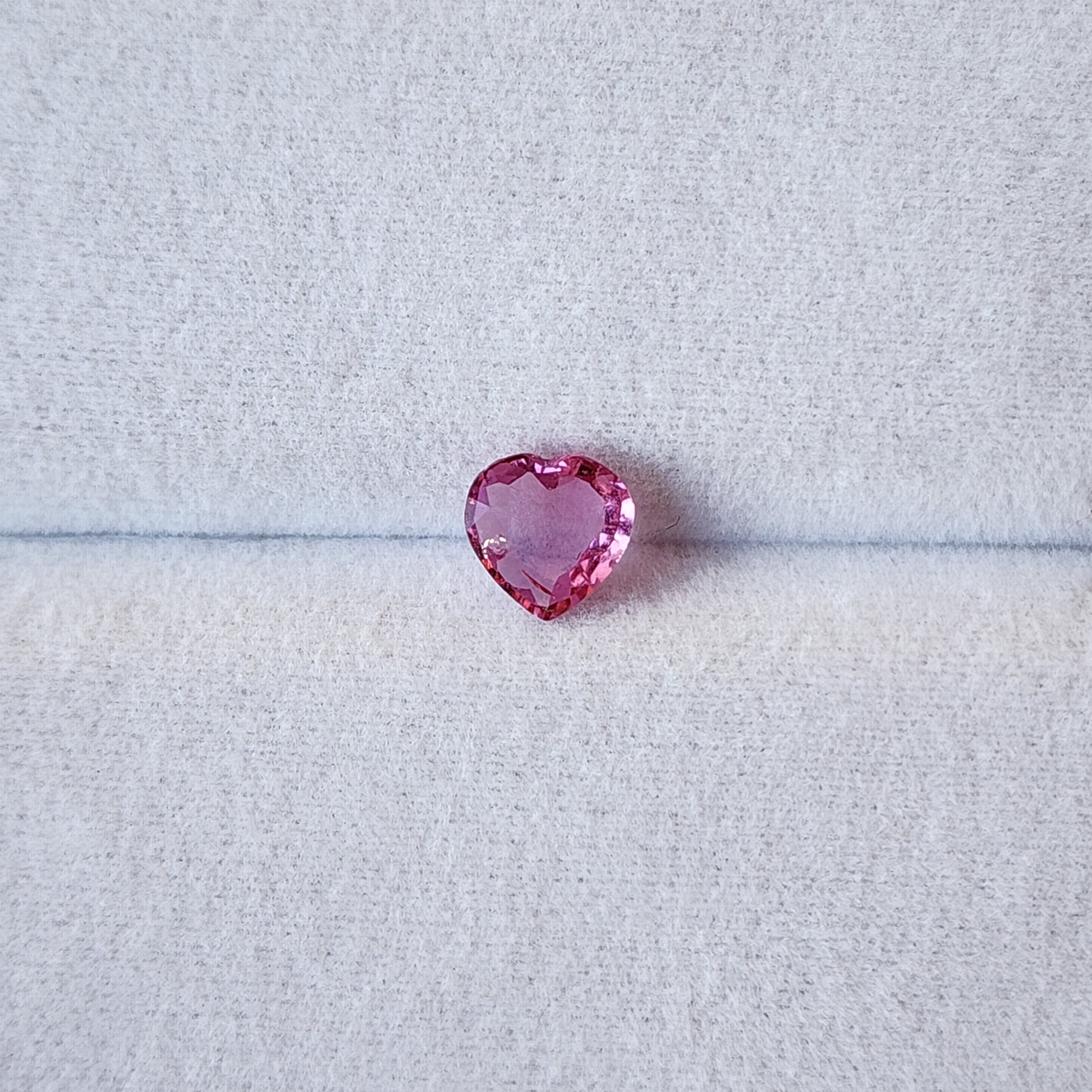 Heart-shaped pink gemstone on a light gray background
