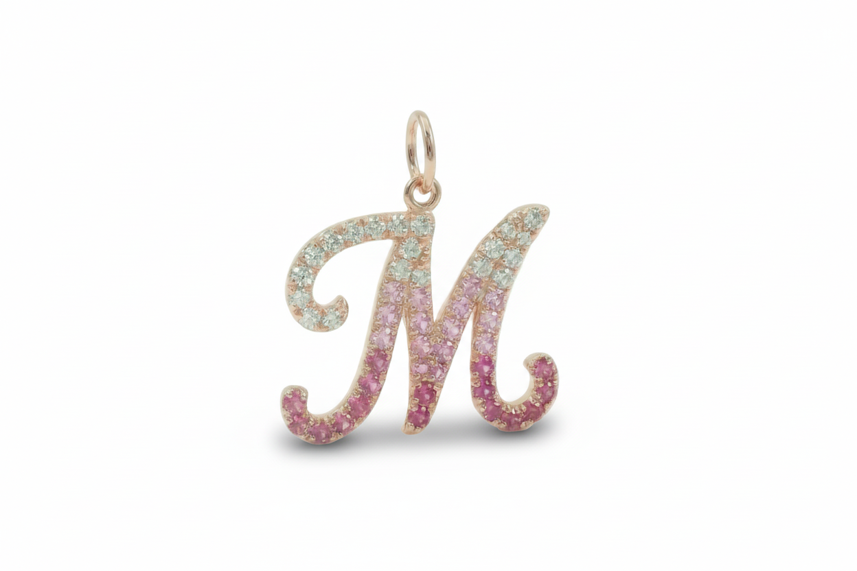Letter 'M' pendant with pink and blue gemstones on a white background