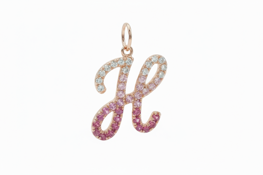 Gold pendant with pink and clear gemstones on a white background
