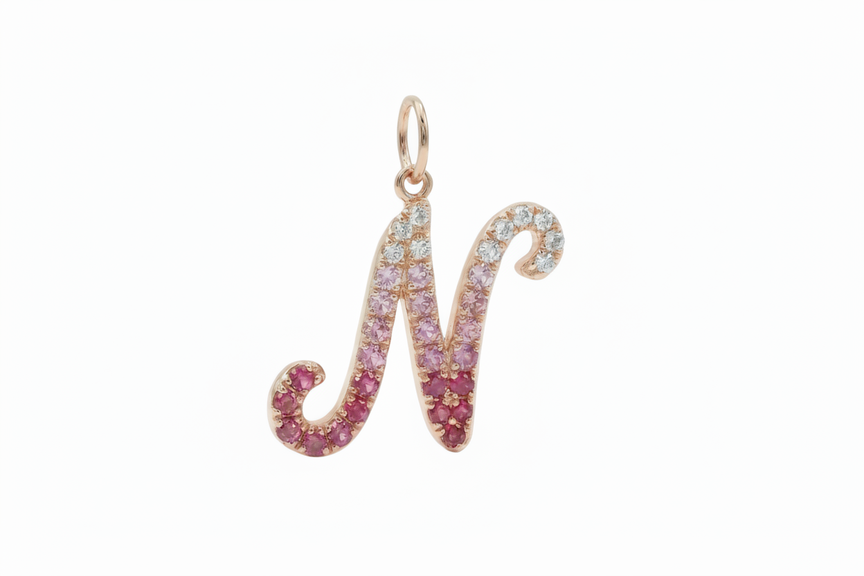 Gold pendant shaped like the letter 'M' with gemstones on a white background