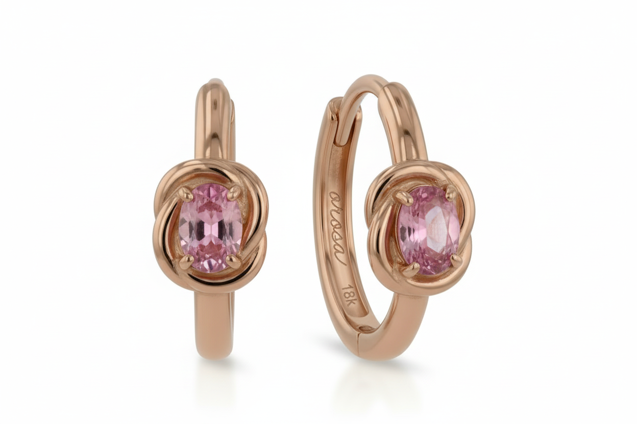 Rose gold hoop earrings with pink gemstones on a white background