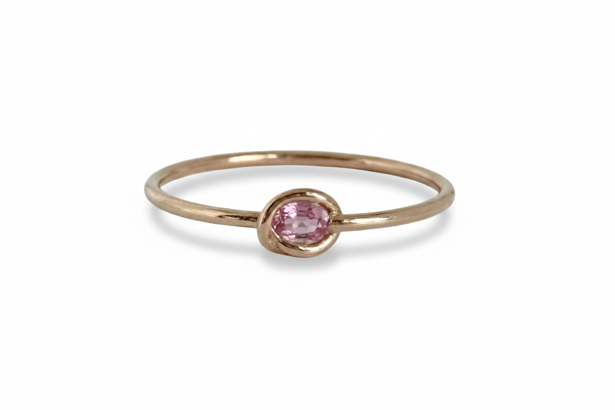 Rose gold bangle with a pink gemstone on a white background